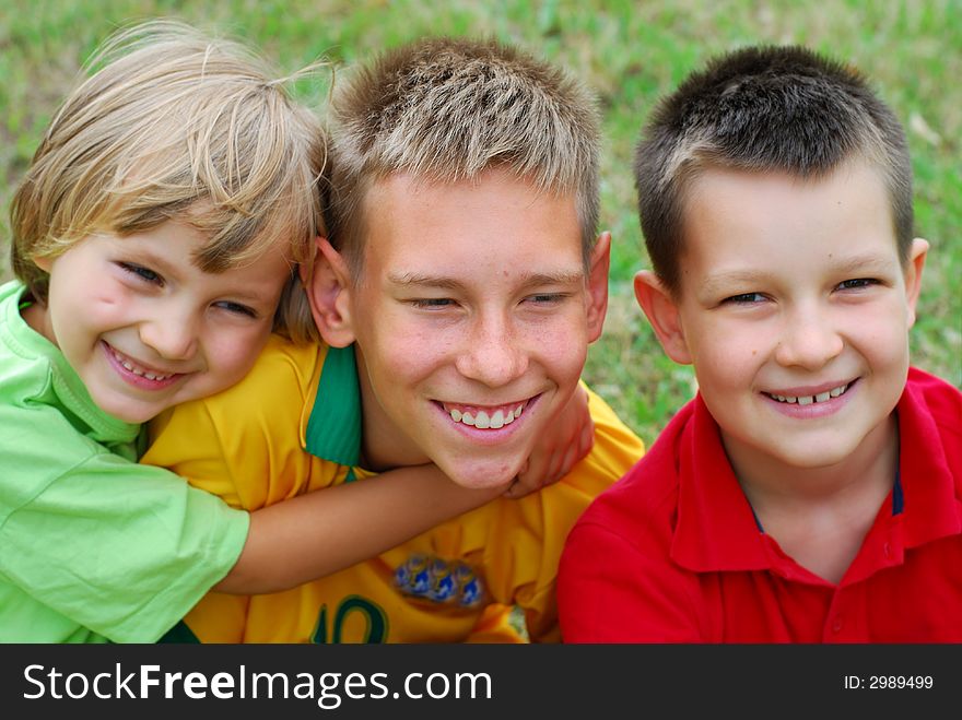 A portrait of three young boys, full of smiles as they pose for a picture outdoors. A portrait of three young boys, full of smiles as they pose for a picture outdoors.