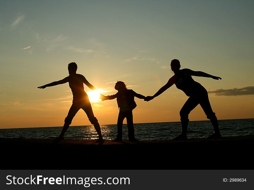 Silhoette of three children holding hands at sunset. Silhoette of three children holding hands at sunset