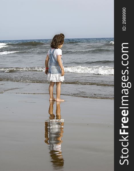 Child is standing on the beach looking at the sea. Child is standing on the beach looking at the sea.