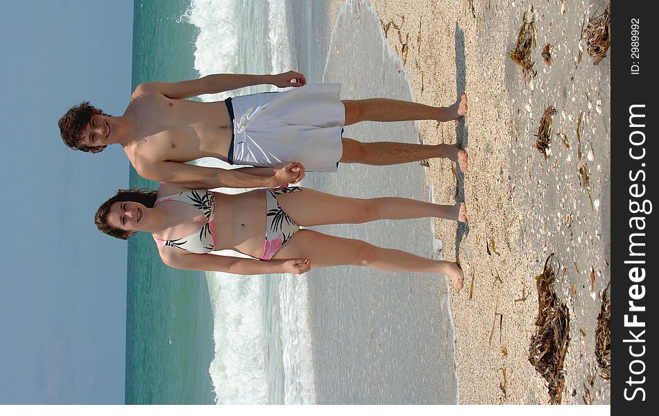 A young couple in swim suits holding hands on the beach. A young couple in swim suits holding hands on the beach