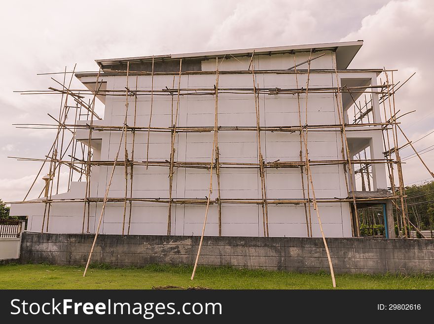Bamboo scaffolding for painting work on building with rain cloudy sky background