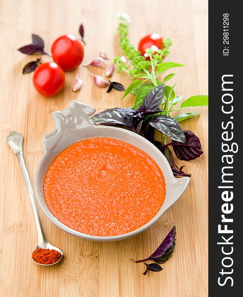 Gazpacho with basil on wooden table