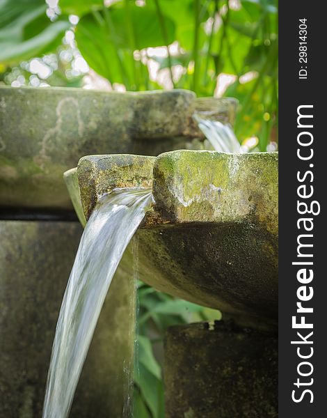 Flowing water from stone basin in the garden