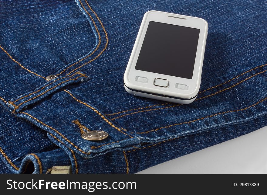 A mobile phone on a pair of blue jeans. A mobile phone on a pair of blue jeans