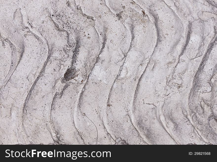 A closeup of dried concrete with vertical wave-like ridges. A closeup of dried concrete with vertical wave-like ridges.