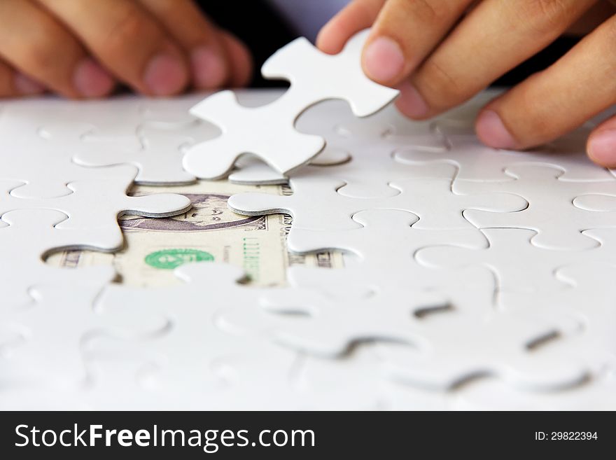 Business man hand holding a puzzle piece, money concept