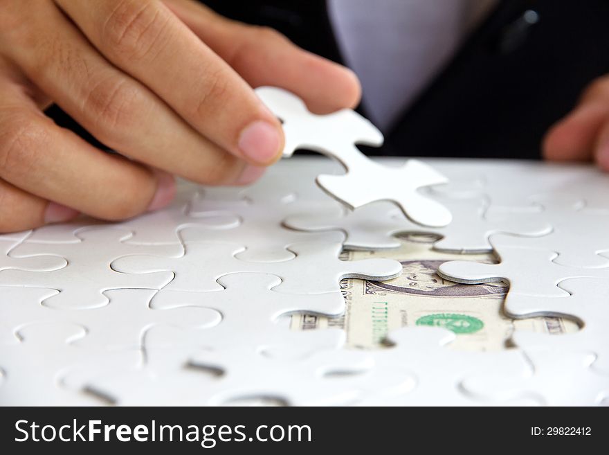 Business man hand holding a puzzle piece, money concept