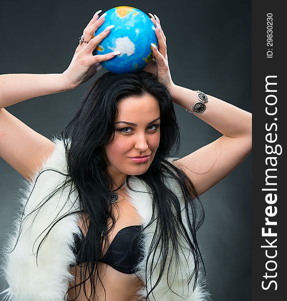Beautiful woman holding a globe on a gray background