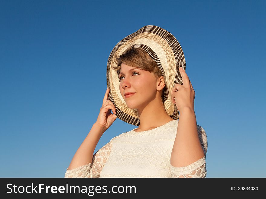 Portrait of young woman near sea holding her hat and looking ahead. Portrait of young woman near sea holding her hat and looking ahead