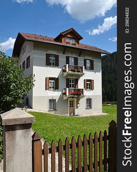 House in Alpine village. Sunny summer day. Dolomites, Val di Fassa, Italy. Vertical frame. House in Alpine village. Sunny summer day. Dolomites, Val di Fassa, Italy. Vertical frame.