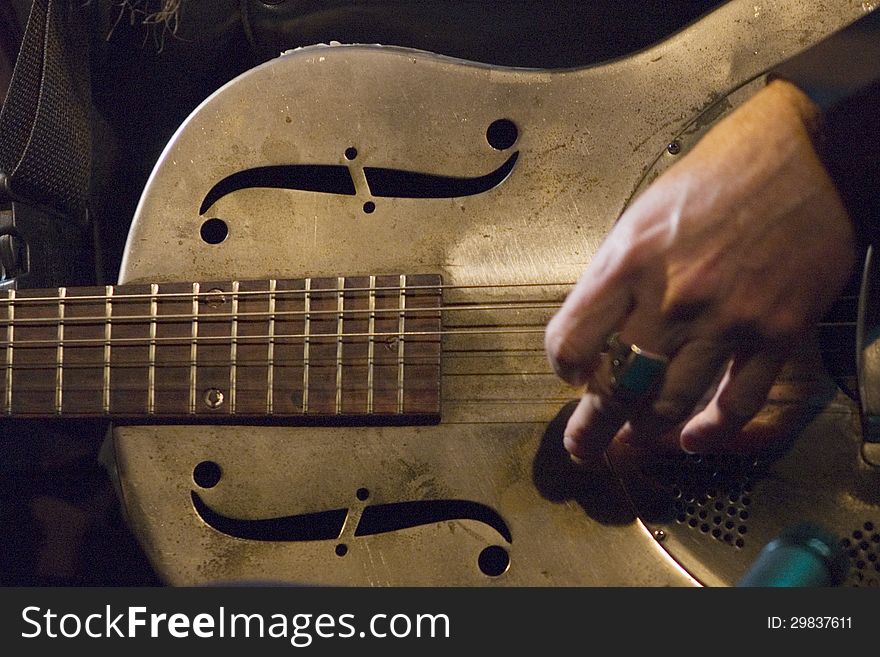 Macro photo with selective focus on the steel guitar, slow shutter with slight movement of hand.