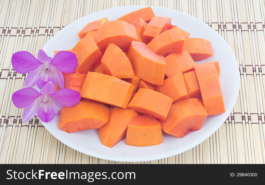 Ripe papaya on dish and dendrobium pompadour