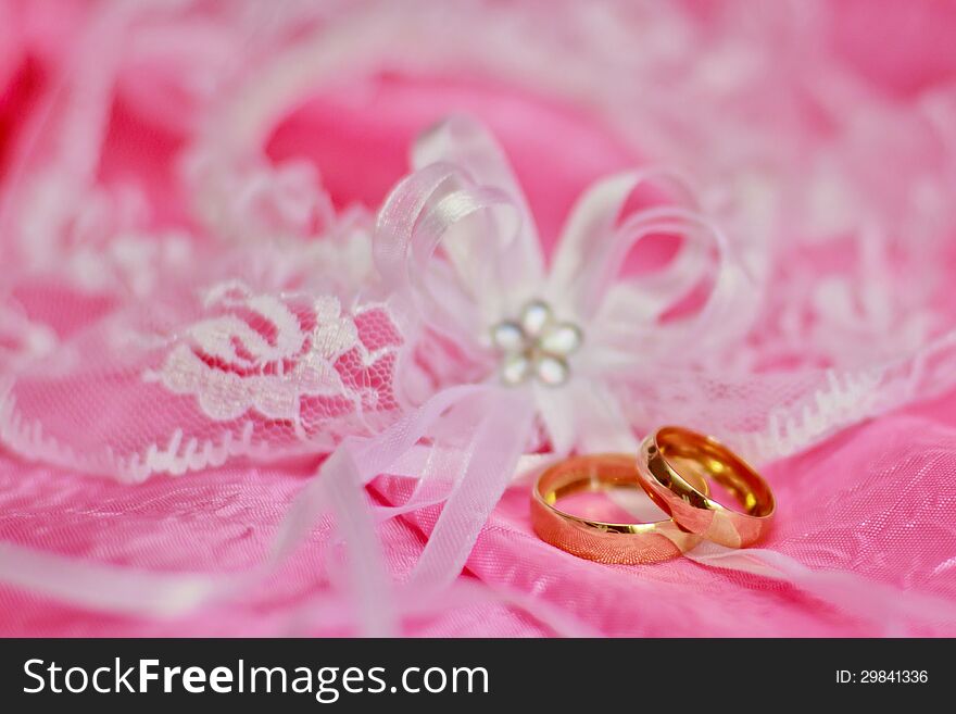Two golden wedding rings on the pink background. Two golden wedding rings on the pink background