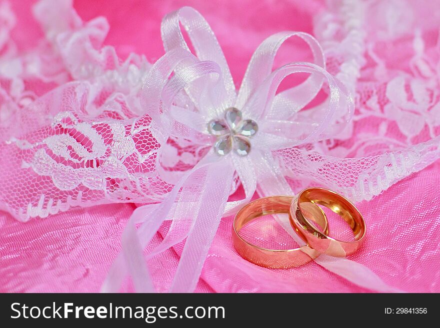 Two golden wedding rings on the pink background. Two golden wedding rings on the pink background