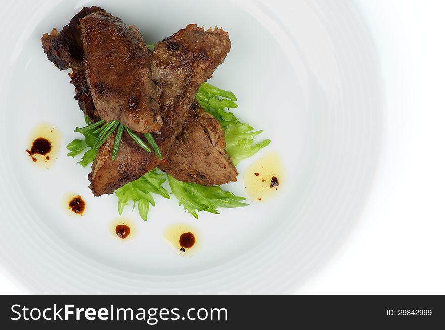 Slices of Delicious Roasted Beef with Spices and Rosemary closeup on White Plate with Lettuce. Top View