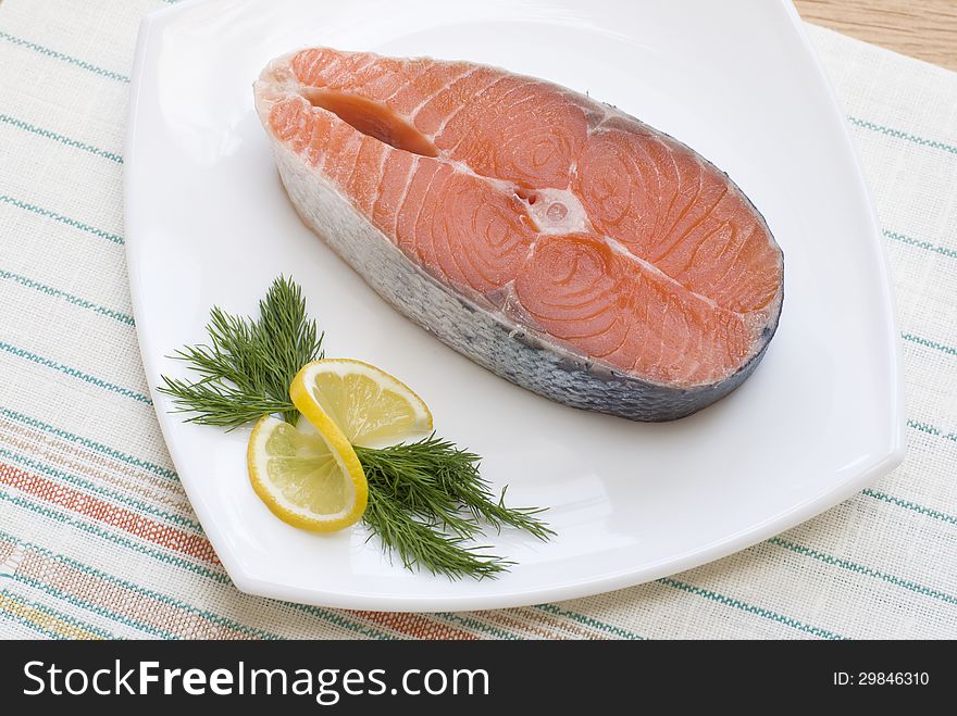 Salmon steak with lemon and dill on white plate