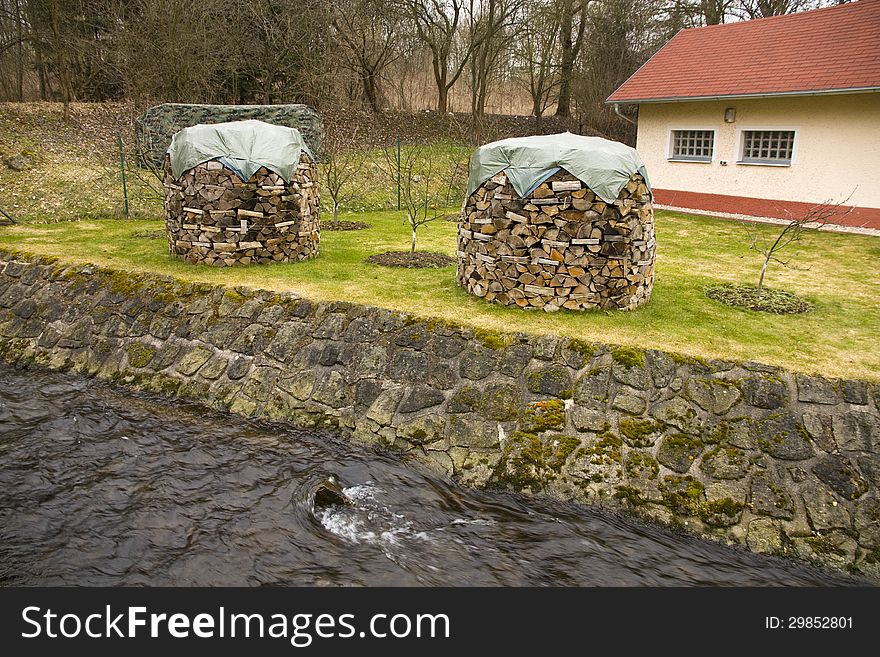 Two piles of wood covered with tarpaulin, two columns of wood in stream. Two piles of wood covered with tarpaulin, two columns of wood in stream