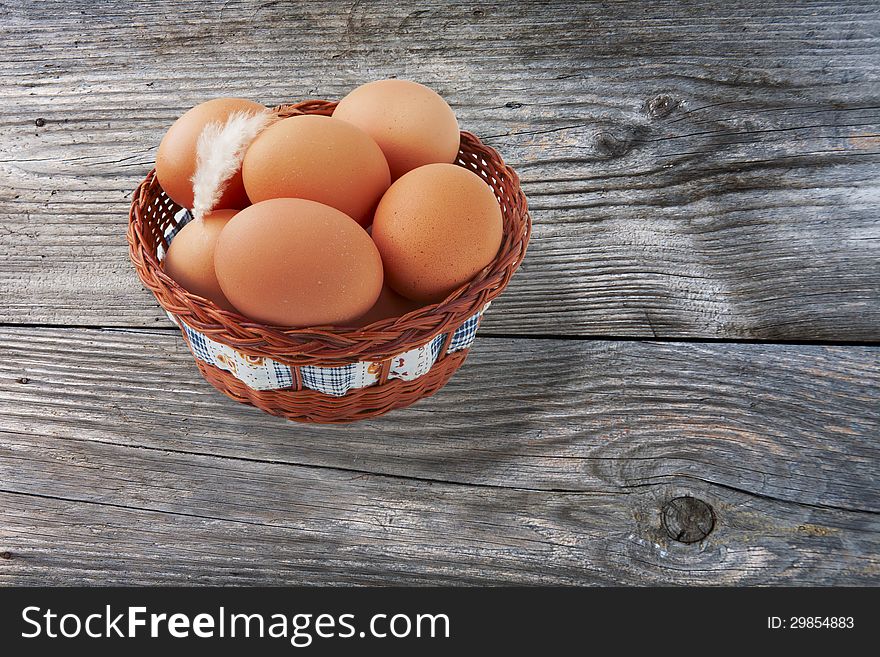 Easter egg and feather in basket on vintage wooden background