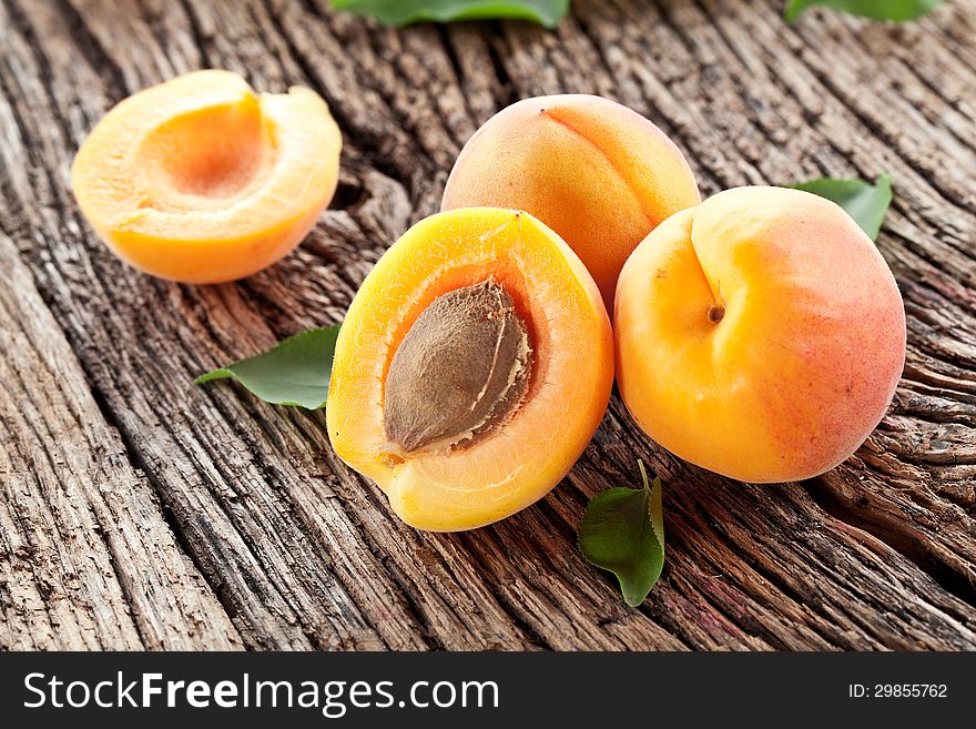 Apricots with leaves on the old wooden table.