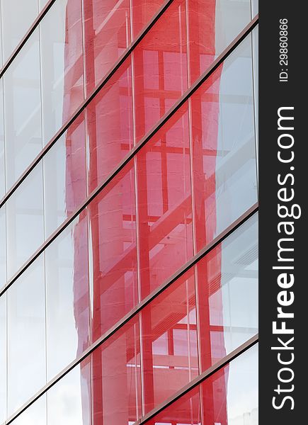 Abstract photo of a contemporary building with blue windows and red reflection.