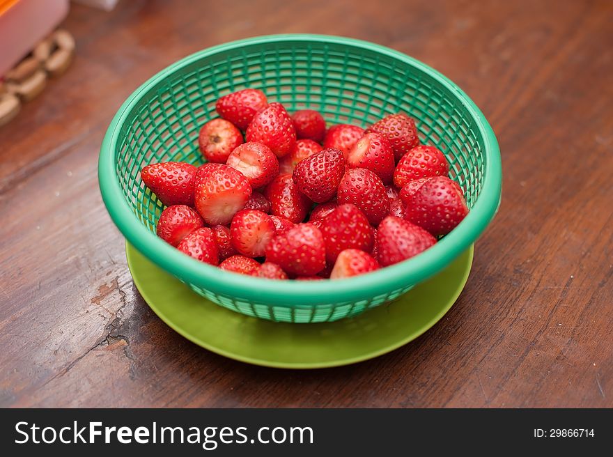 Strawberries in green basket on wooden desk. Strawberries in green basket on wooden desk