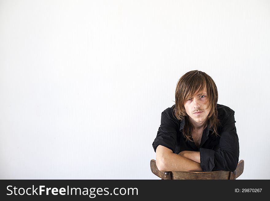 Portrait of the thoughtful young guy sitting on a chair