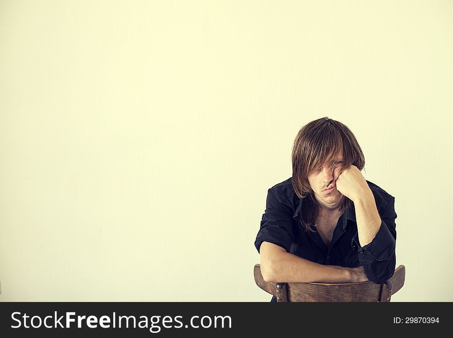 Portrait of the thoughtful young guy sitting on a chair