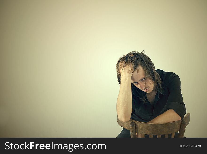 Portrait of the thoughtful young guy sitting on a chair