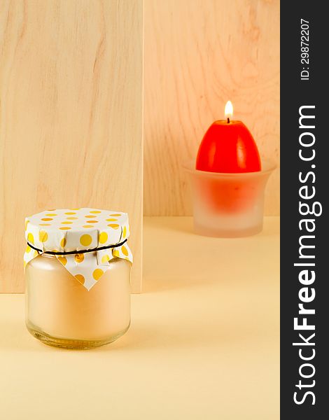 Easter treat - peachy jam and a burning candle in the shape of an egg on a light background of wood an alder. Easter treat - peachy jam and a burning candle in the shape of an egg on a light background of wood an alder