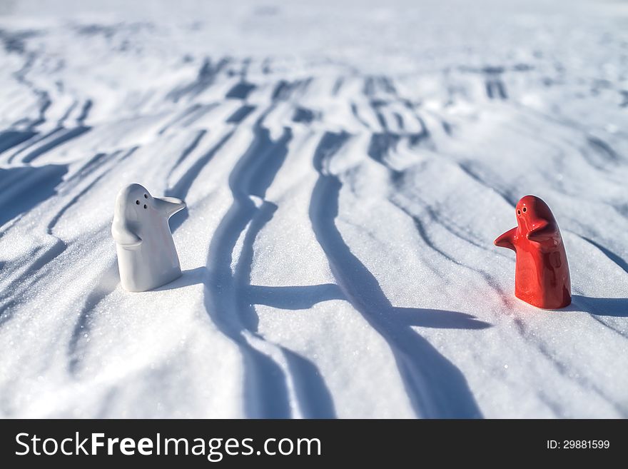 Two little lonely white and red people stay on snow field