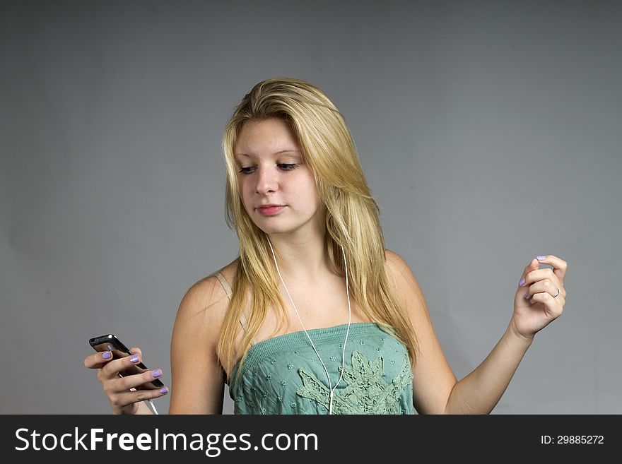 A teenage girl listening to music on a portable device and following the rhythm by snapping her fingers. A teenage girl listening to music on a portable device and following the rhythm by snapping her fingers