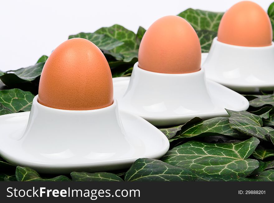 Three eggs and egg cups on a green background. Three eggs and egg cups on a green background