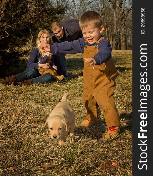 A young boy chases his puppy as his family watches. A young boy chases his puppy as his family watches