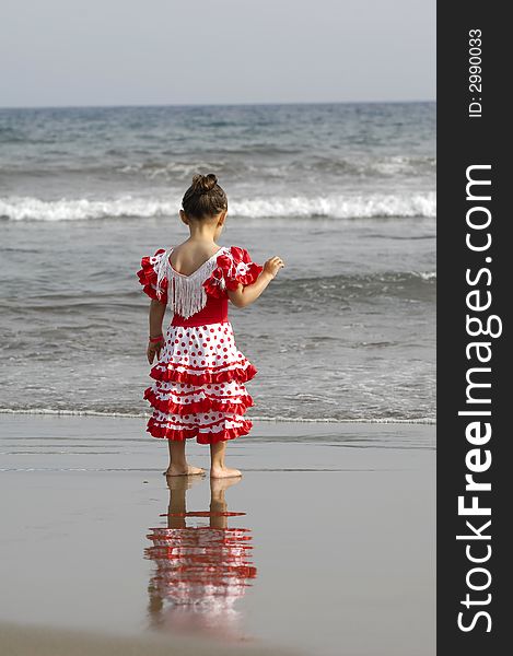 Child is standing on the beach looking at the ocean. Child is standing on the beach looking at the ocean.