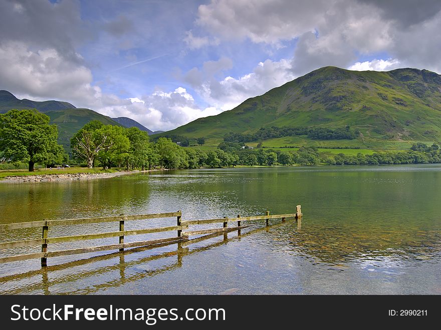 A partially submerged fence on the shore of Buttermere in the English Lake District. A partially submerged fence on the shore of Buttermere in the English Lake District