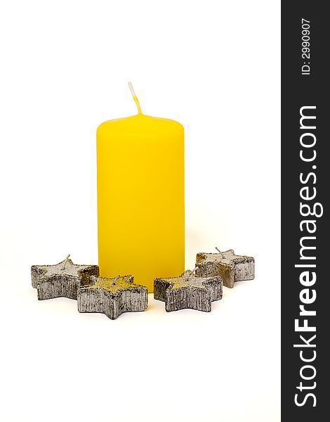 Big yellow candle and four silver star-shaped candles. Big yellow candle and four silver star-shaped candles
