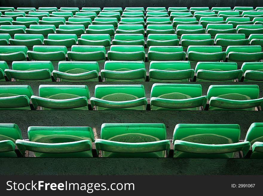 Many plastic green seats on football stadium