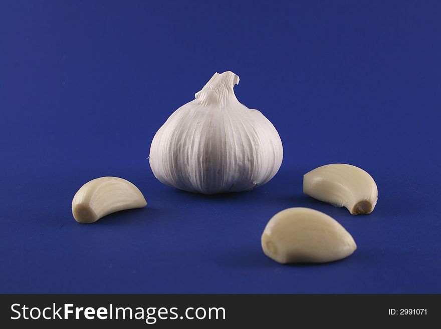 A bulb of garlic and some cloves, on a blue background. A bulb of garlic and some cloves, on a blue background.