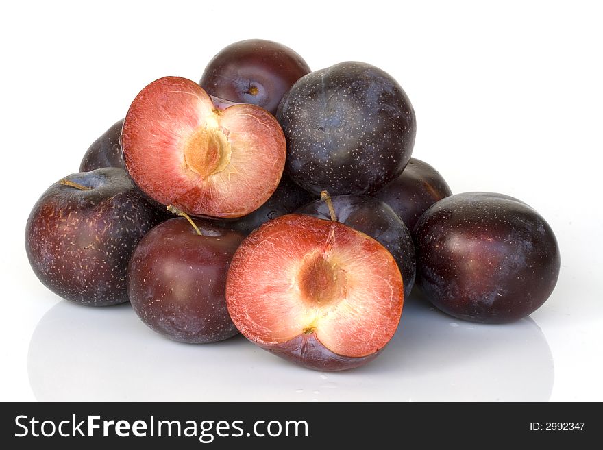 Stack of plums with one cut open isolated on white background. Stack of plums with one cut open isolated on white background