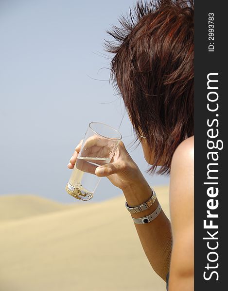 A woman is drinking water in the desert. A woman is drinking water in the desert.