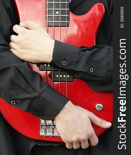 Young man embracing a red bass guitar. Young man embracing a red bass guitar