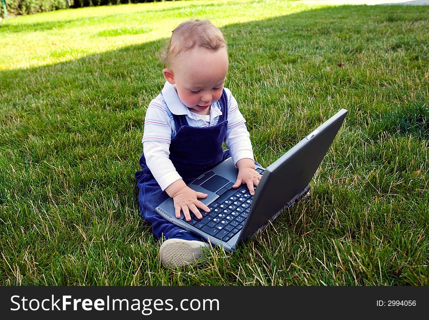 Baby study on computer on lawn