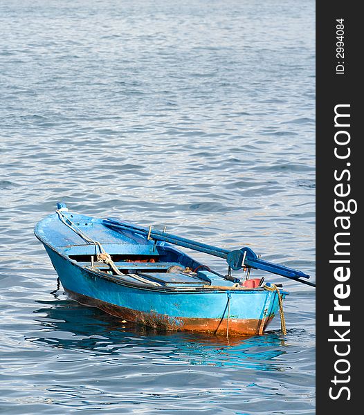 Small blue painted boat sits at anchor. Small blue painted boat sits at anchor