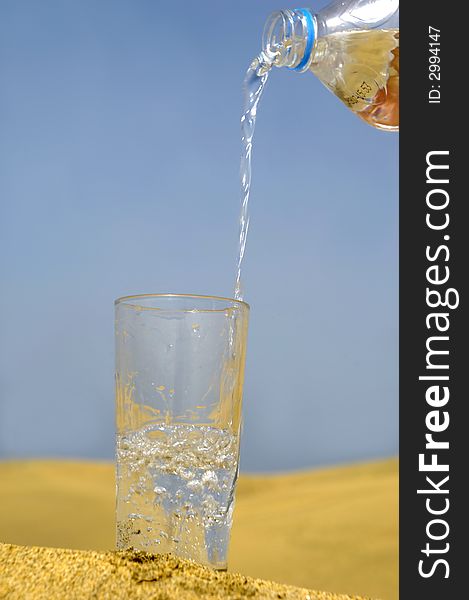 A glass of fresh water and bottle in a desert. A glass of fresh water and bottle in a desert