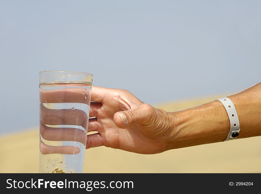 Hand is reaching for a fresh glass of cold water in desert. Hand is reaching for a fresh glass of cold water in desert.