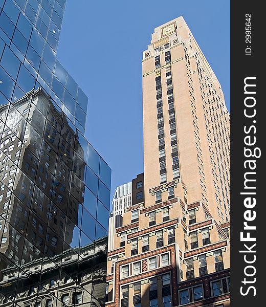 A composition of old and new buildings in New York City against a blue sky. A composition of old and new buildings in New York City against a blue sky.
