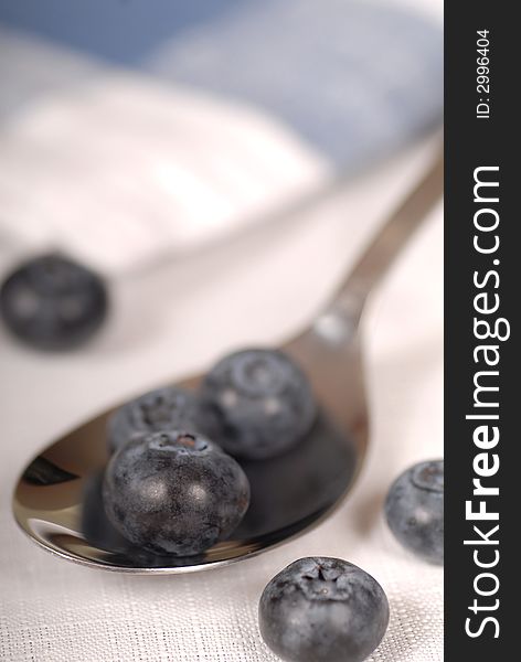 Fresh blueberries resting in a spoon and on a napkin