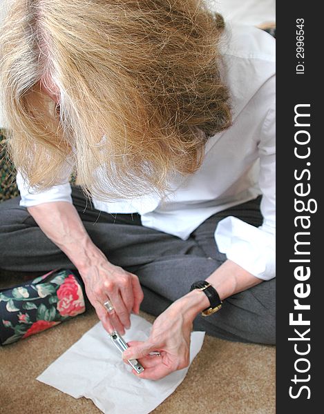 Woman clipping her nails in her bedroom. Woman clipping her nails in her bedroom.