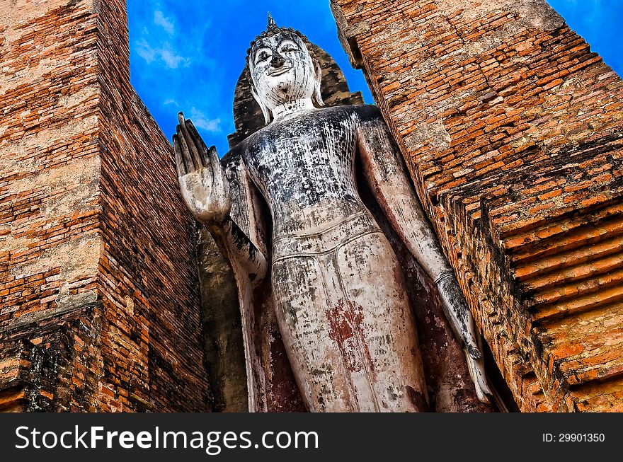 Large standing stone Buddha with hand gesture in Sukhothai historical park (Wat Mahathat), Thailand. Large standing stone Buddha with hand gesture in Sukhothai historical park (Wat Mahathat), Thailand