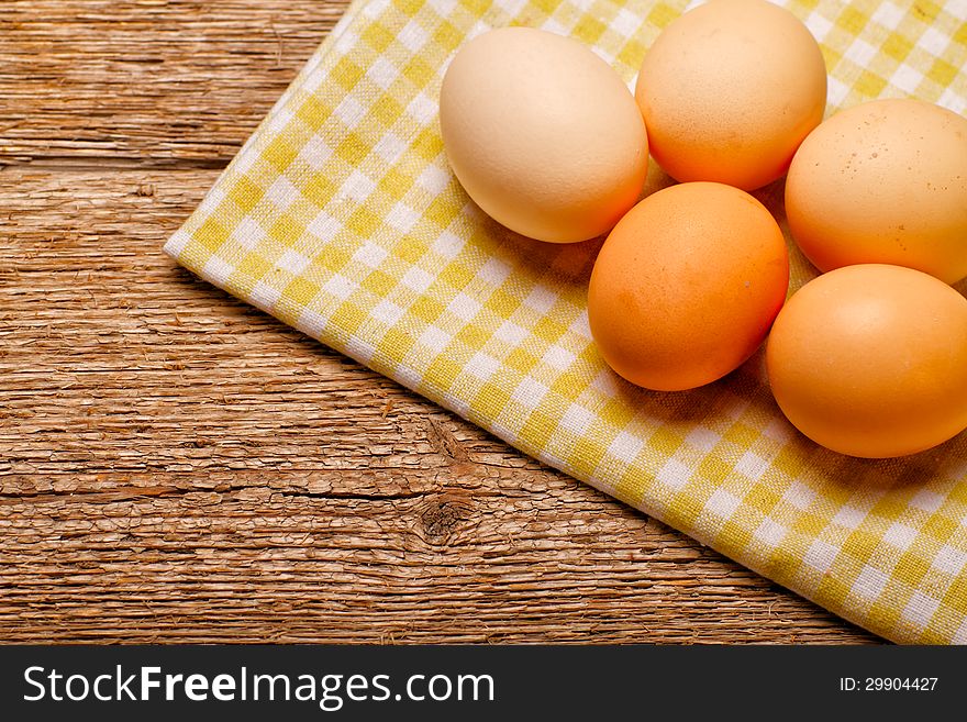 Eggs on rustic tablecloth over wooden background